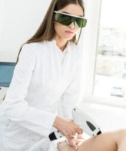 young hair removal therapist in coat with laser epilator looking at camera